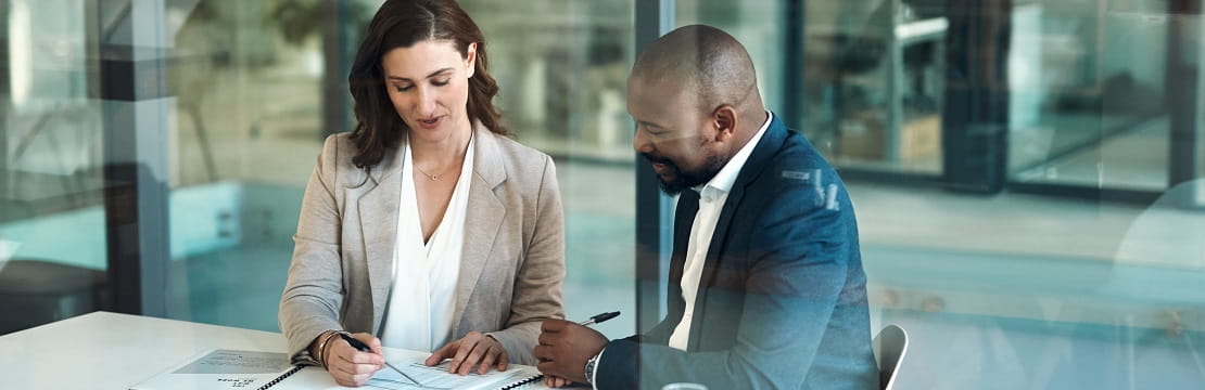 Man and woman sit together at a table reviewing documents.